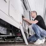 a man servicing the exterior of an RV recreational vehicle